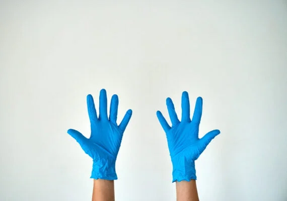 Two hands preparing to wear Disposable Blue Nitrile Gloves - Medical Grade, Latex & Powder-Free for enhanced protection.